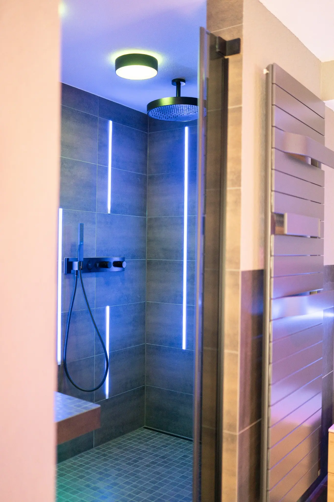 Blick in die bodengleiche Dusche mit Regenbrause und Lichtprofilen