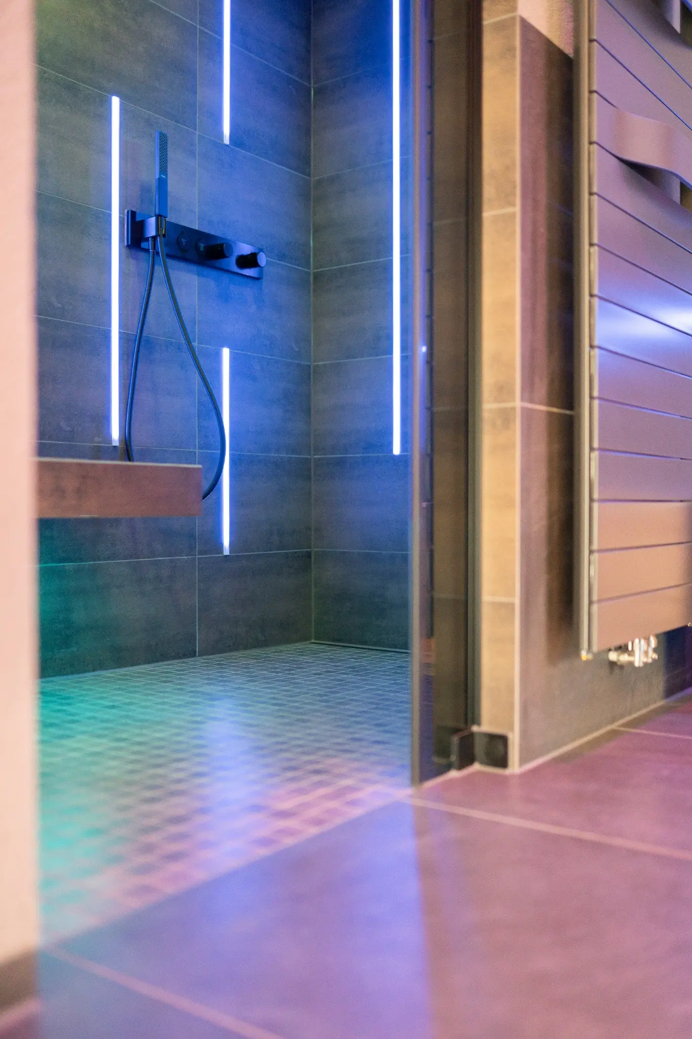 Raumansicht der Dusche mit Sitzbank und farbigem Licht