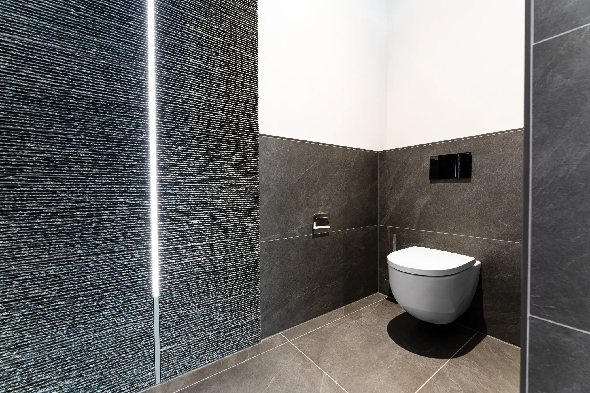 Separater WC-Bereich mit strukturiertem Wandbelag und integriertem Lichtprofil