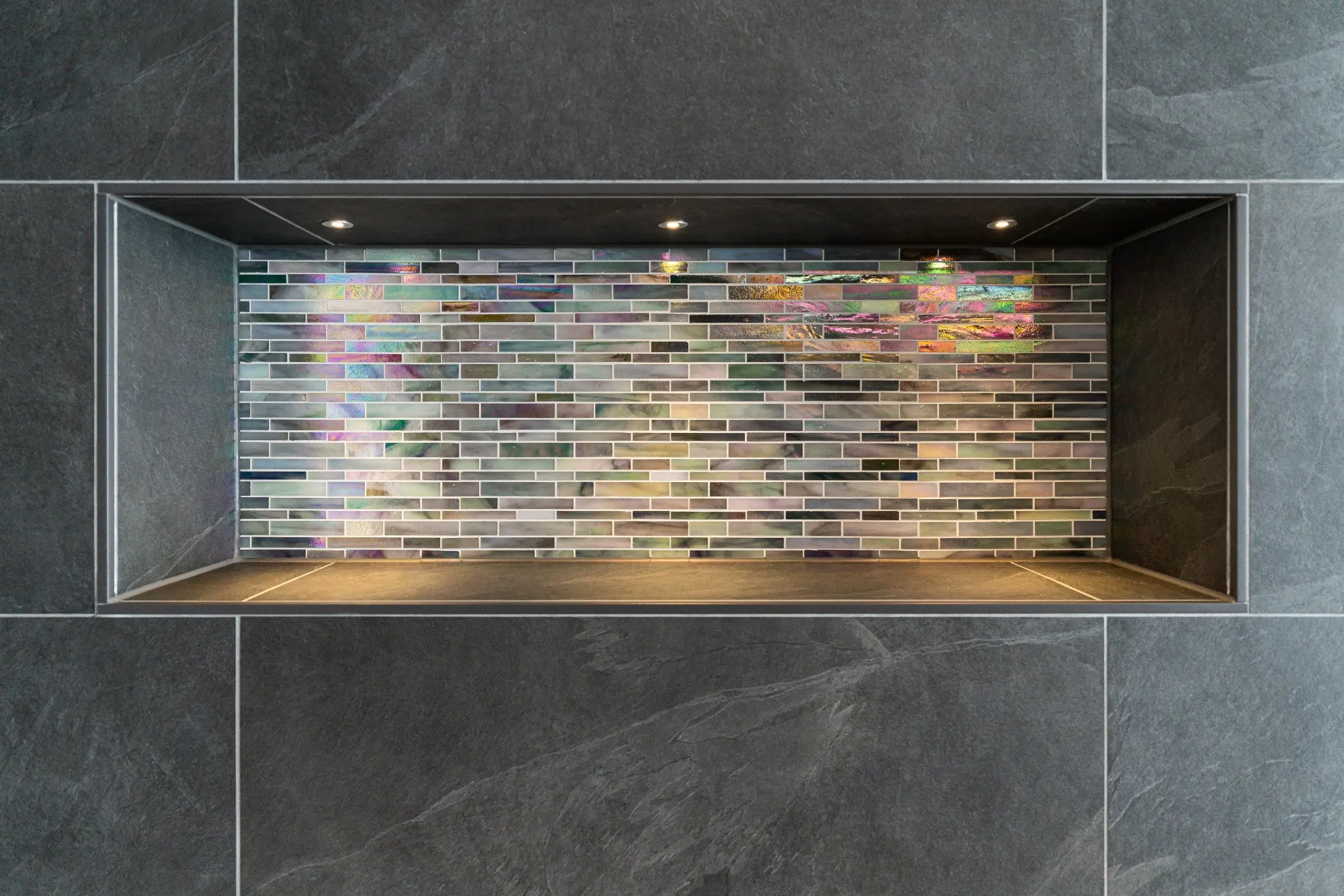 Beleuchtete Wandnische mit irisierendem Mosaik und Regenbogeneffekt